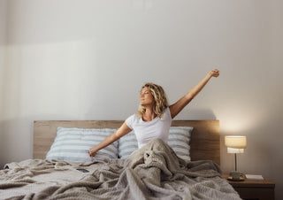 Woman doing morning stretches in bed after waking up