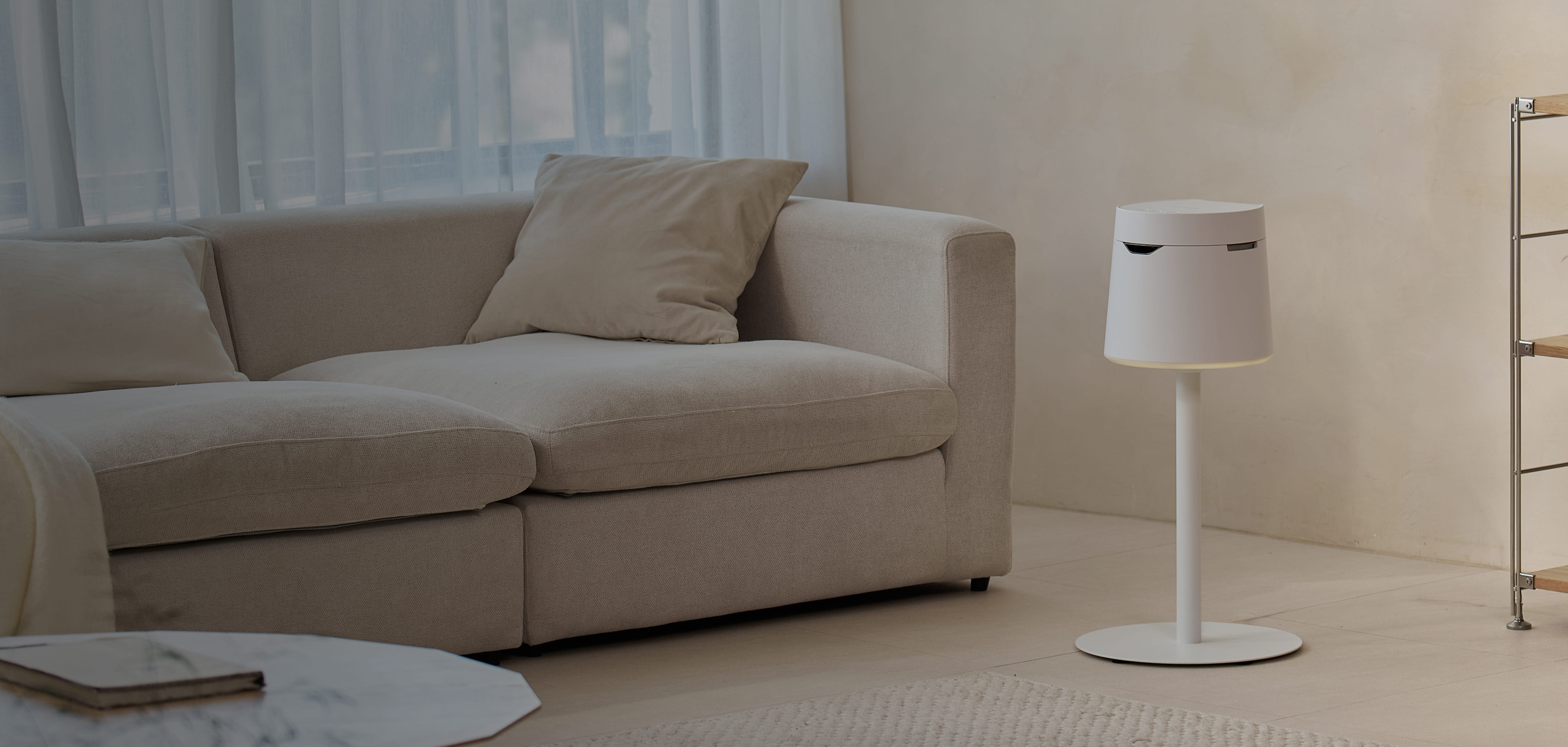 White Carepod humidifier with a cylindrical shape and a round base, next to a beige sofa