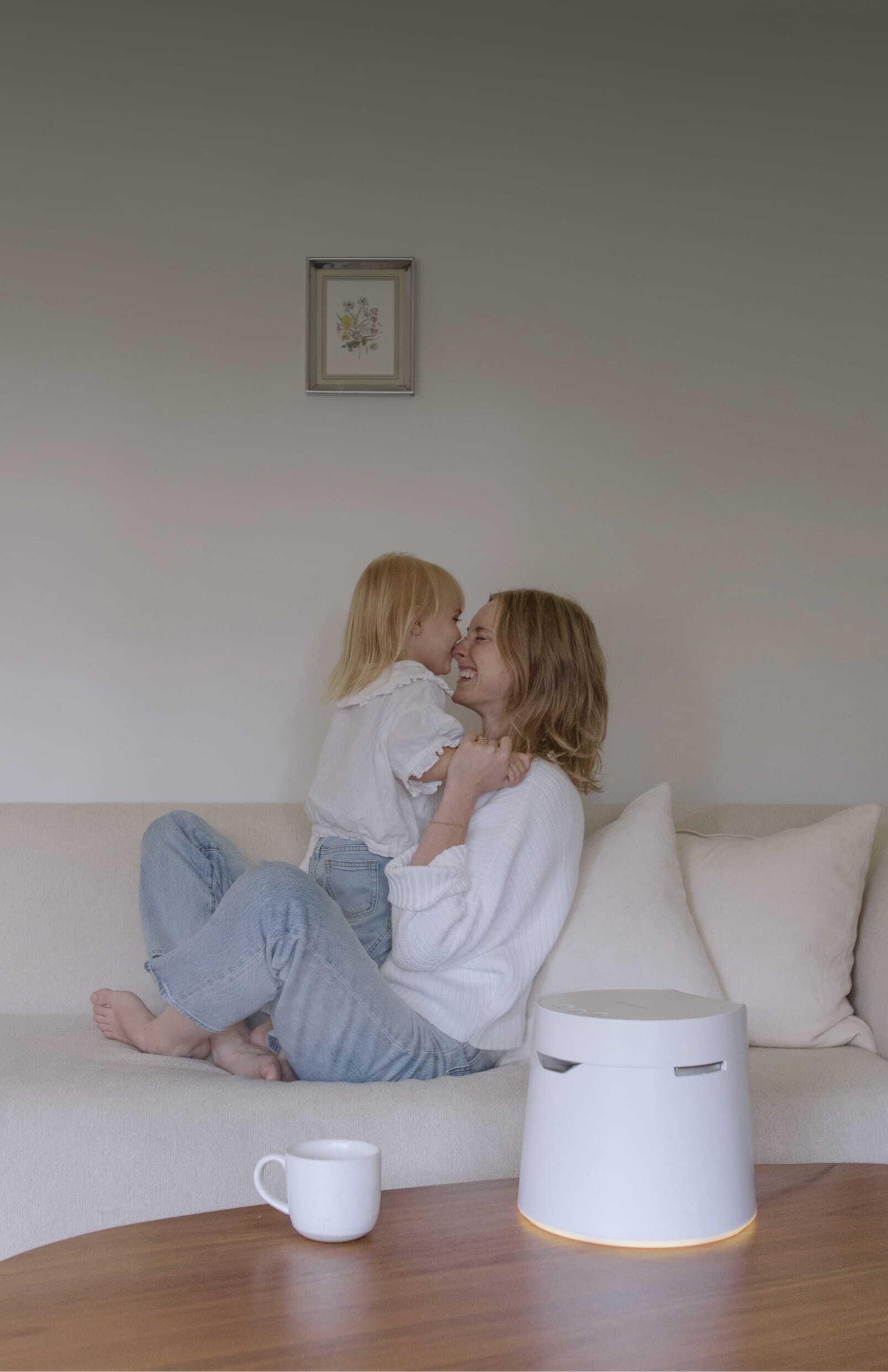 Mother and child on a couch with a white mug and a white humidifier on a wooden table