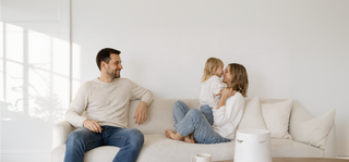 Family of three on a sofa, with a man smiling at a woman and child